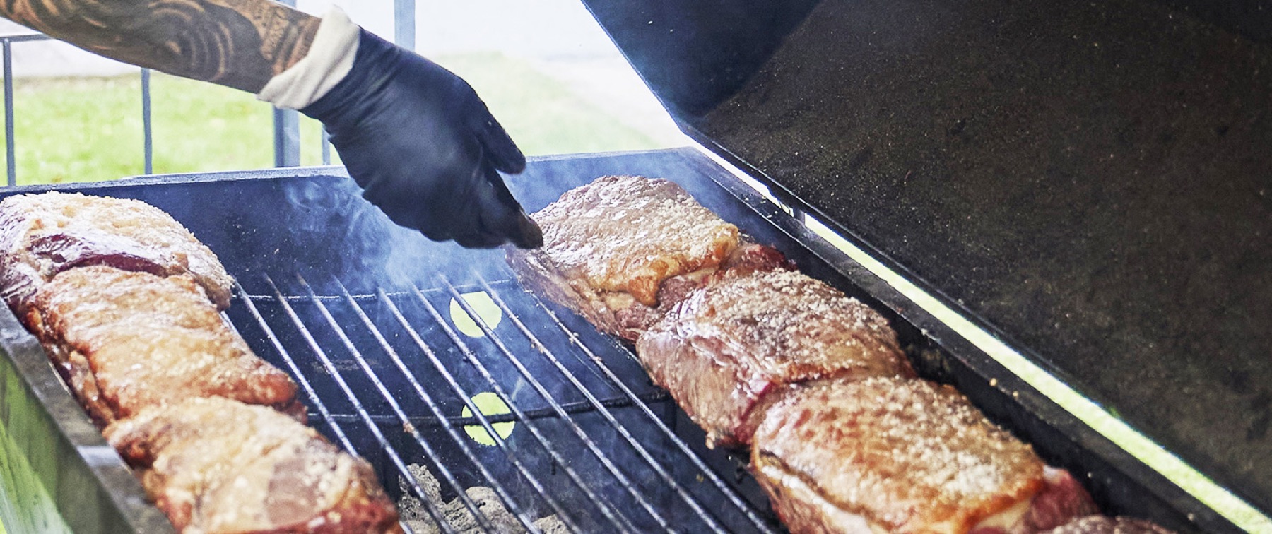 Grillmester med bøffer på grillen